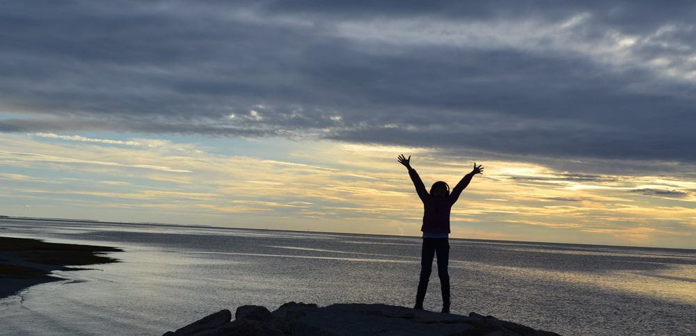 Woman standing with arms raised into a V